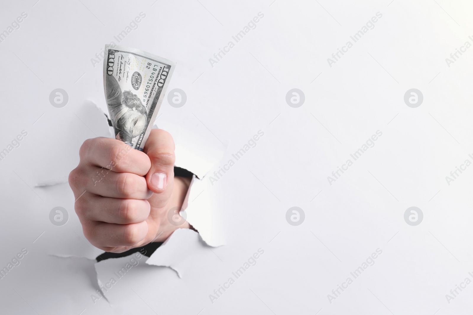 Photo of Man breaking through white paper with money in fist, closeup. Space for text