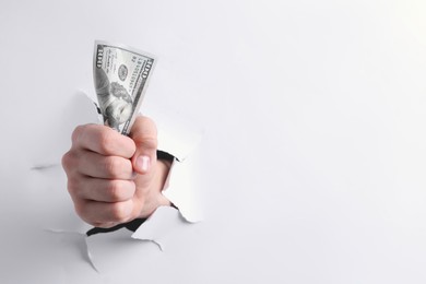 Photo of Man breaking through white paper with money in fist, closeup. Space for text