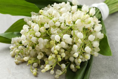 Photo of Beautiful lily of the valley bouquet on grey table, closeup
