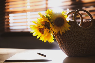 Bouquet of beautiful sunflowers, notebook and pencil on table indoors. Space for text