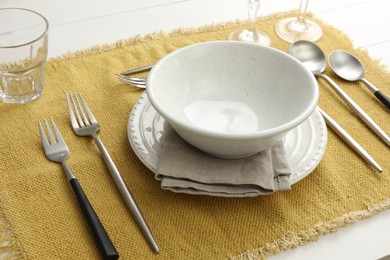 Photo of Stylish setting with cutlery, dishes and napkin on white wooden table