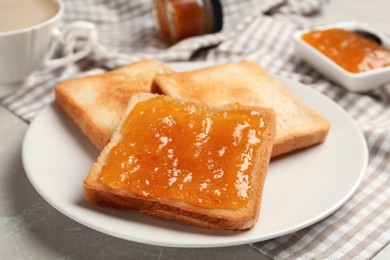 Photo of Toast with tasty orange jam and roasted slices of bread on table, closeup