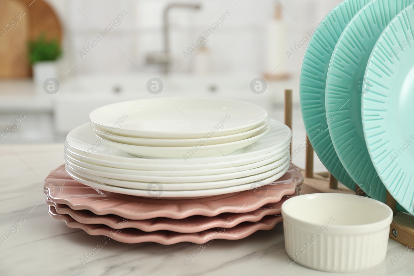 Photo of Clean plates and bowl on white marble table in kitchen