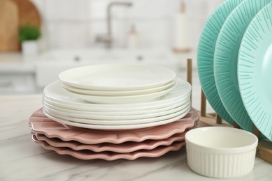 Photo of Clean plates and bowl on white marble table in kitchen