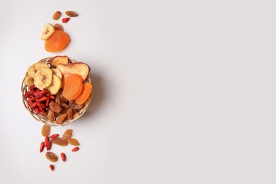 Photo of Wicker basket with different dried fruits on white background, top view. Space for text