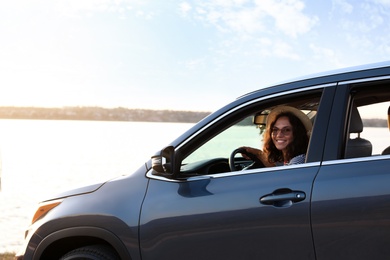 Photo of Young beautiful woman sitting in family car on riverside