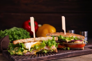 Photo of Wooden board with tasty sandwiches on table