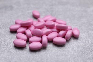 Photo of Many pink dragee candies on grey textured background, closeup