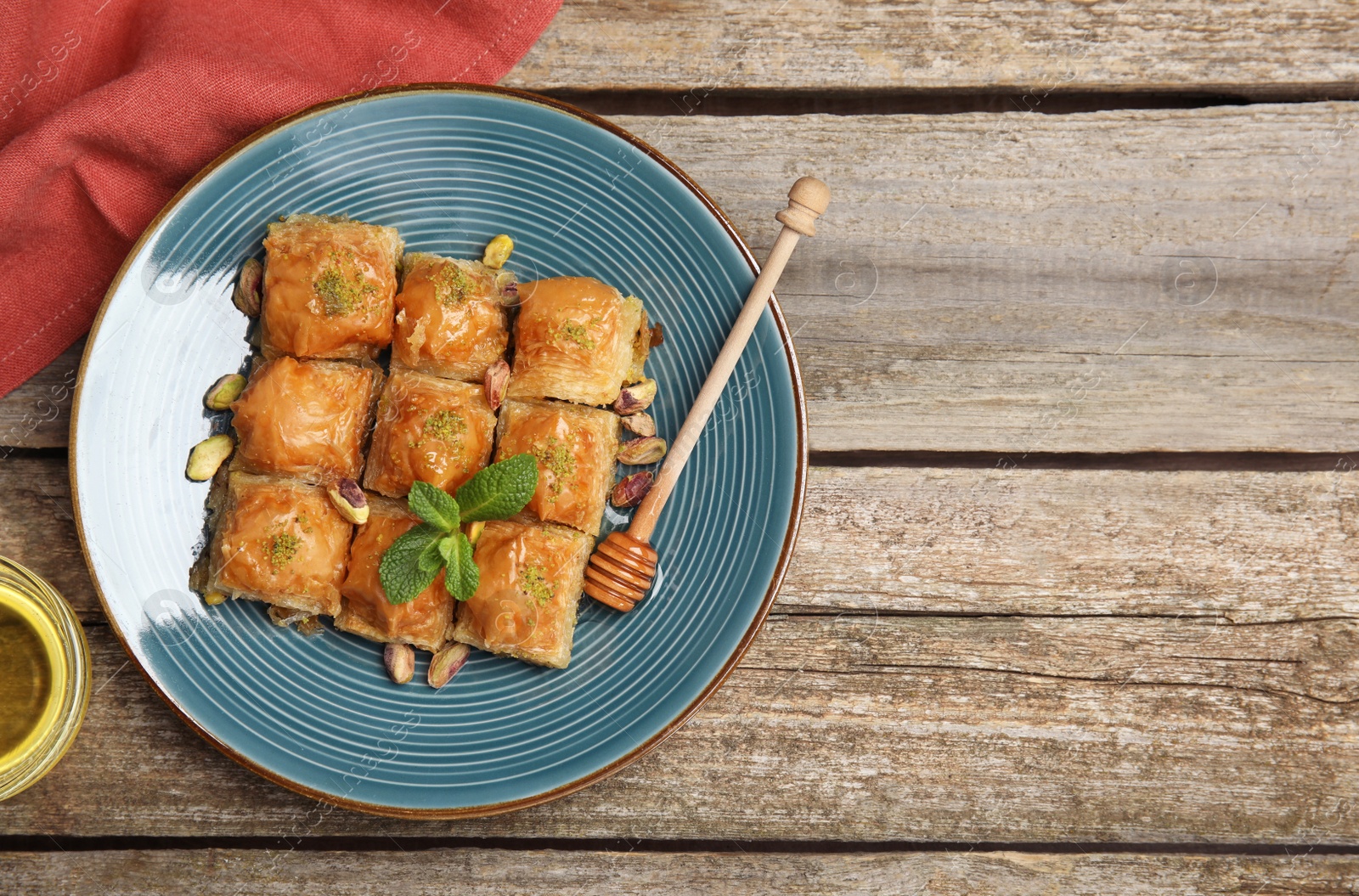 Photo of Delicious baklava with pistachios, honey and mint on wooden table, flat lay. Space for text