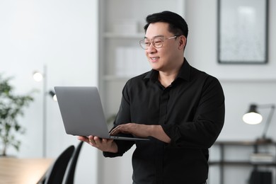 Portrait of smiling businessman with laptop in office