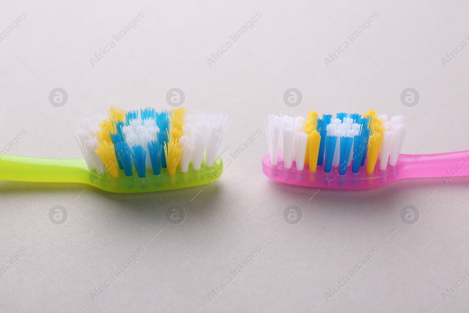 Photo of Colorful plastic toothbrushes on light background, closeup