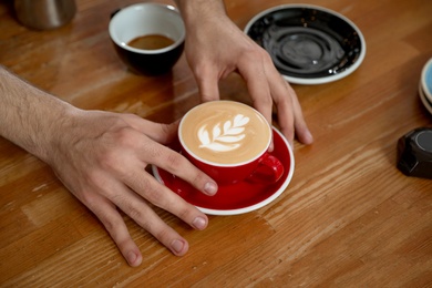 Photo of Barista putting cup of coffee on table, closeup