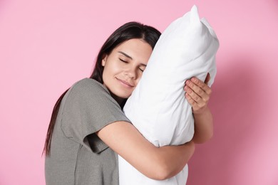 Photo of Sleepy young woman with soft pillow on pink background