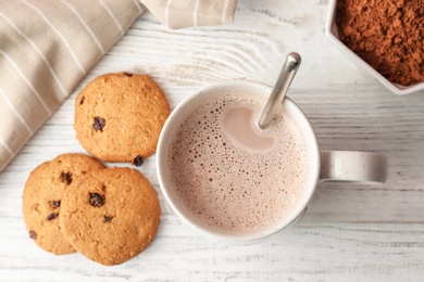 Tasty cookies and mug with hot cocoa drink on table, top view