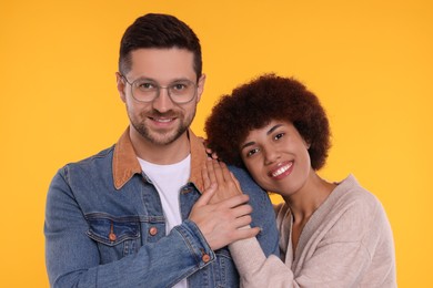International dating. Portrait of happy couple on orange background