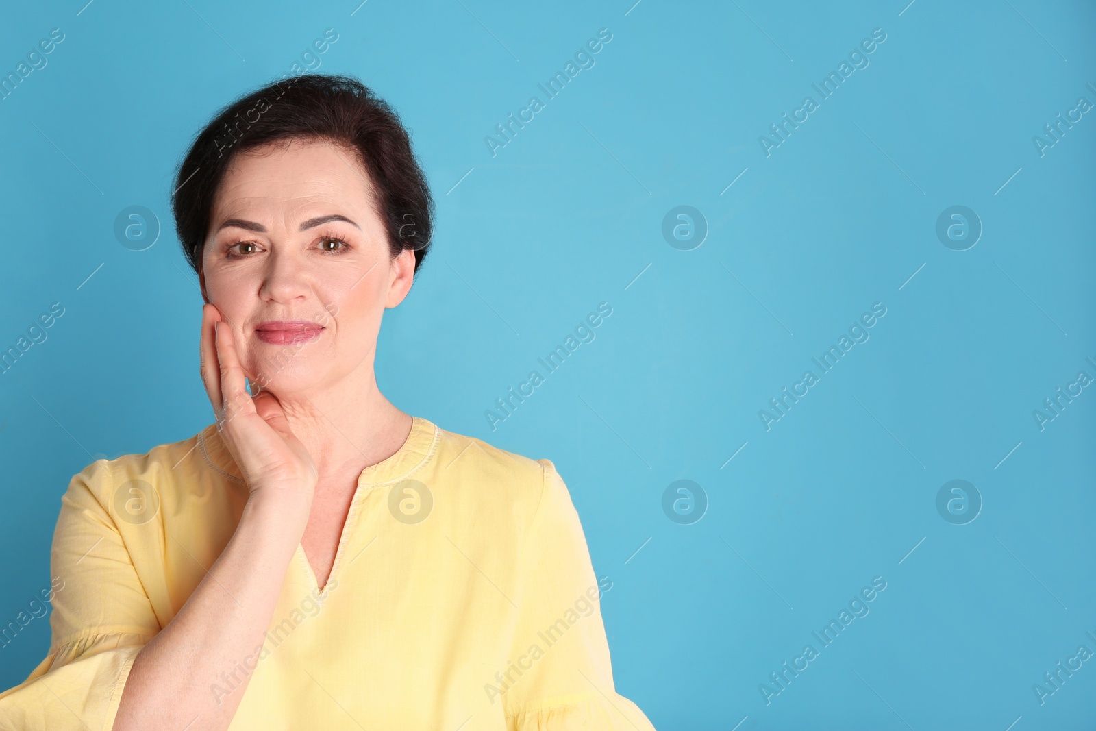 Photo of Portrait of charming mature woman with healthy beautiful face skin and natural makeup on blue background, space for text