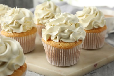 Photo of Tasty cupcakes with vanilla cream on grey table, closeup