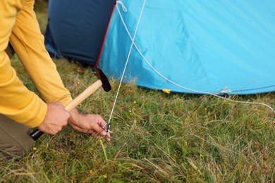 Photo of Man setting up camping tent outdoors, closeup