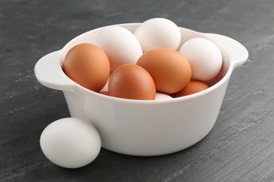 Photo of Unpeeled boiled eggs in saucepan on dark grey table, closeup