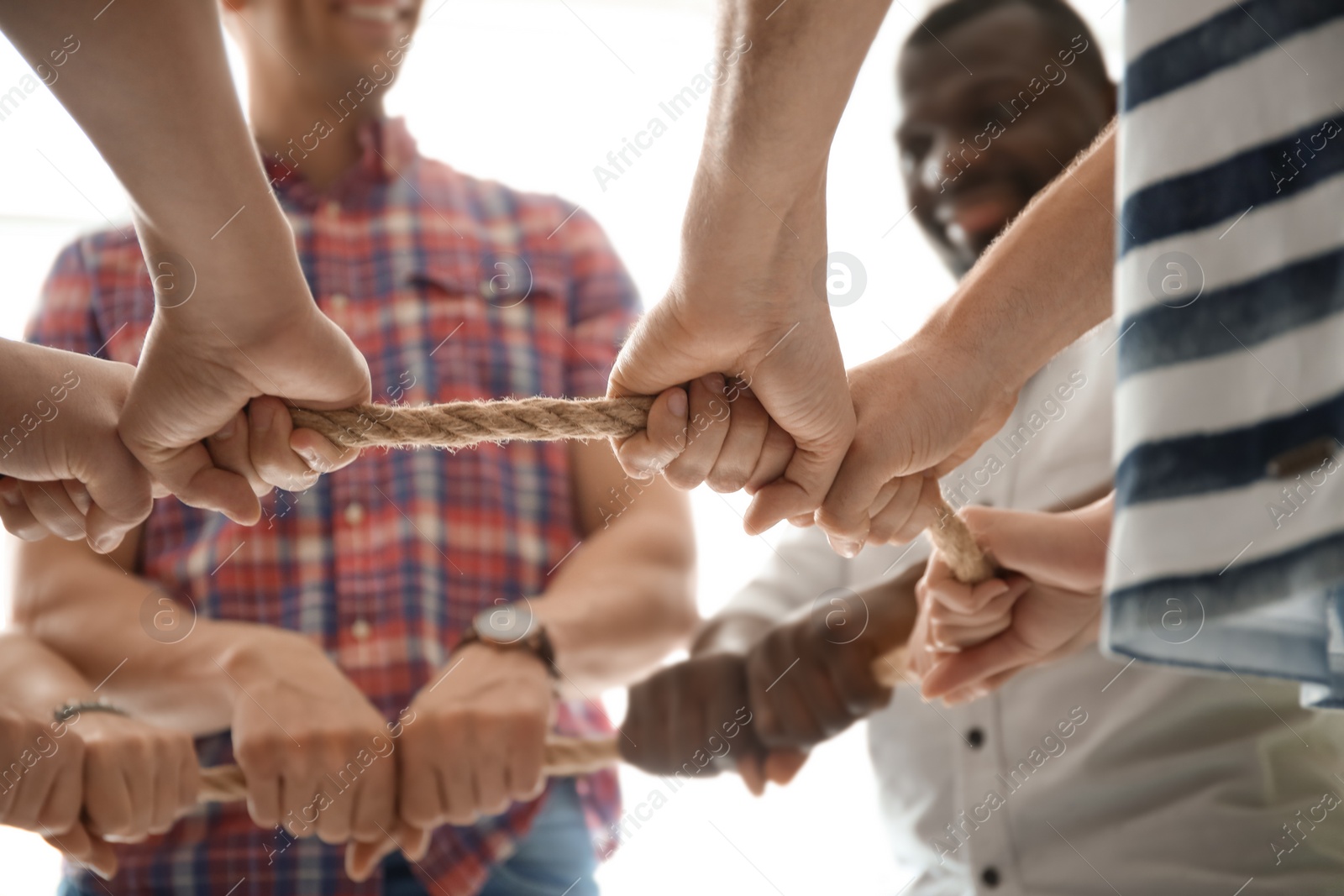 Photo of People holding rope together on light background, closeup of hands. Unity concept