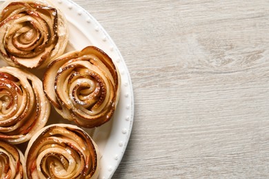 Freshly baked apple roses on white wooden table, top view. Space for text