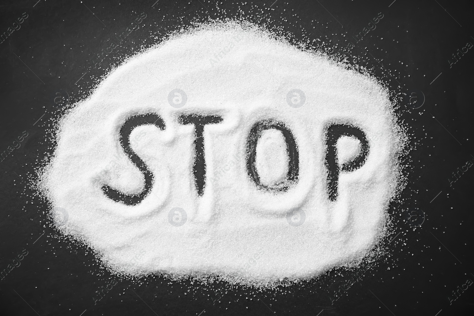 Photo of Word STOP written on sugar sand