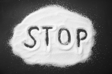 Word STOP written on sugar sand