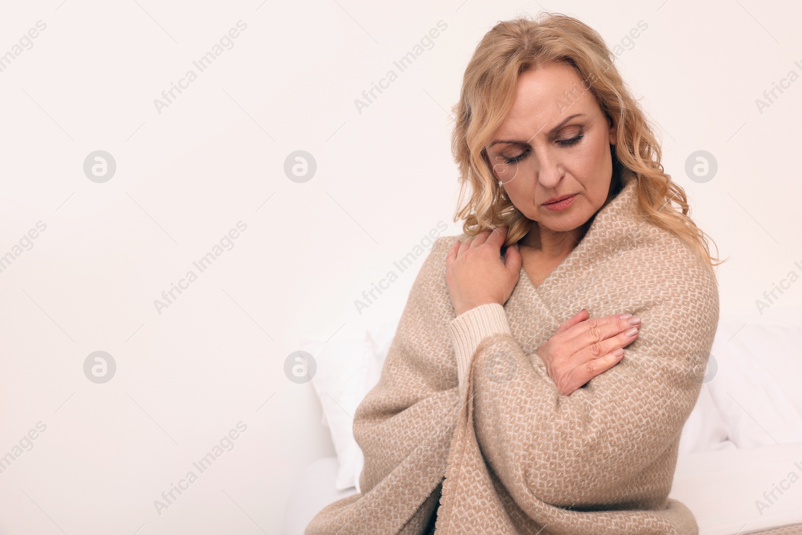 Photo of Upset middle aged woman wrapped in plaid at home, space for text. Loneliness concept