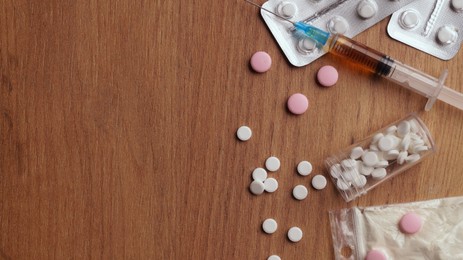 Photo of Different hard drugs on wooden table, flat lay. Space for text