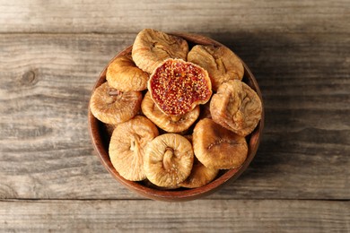 Bowl with tasty dried figs on wooden table, top view