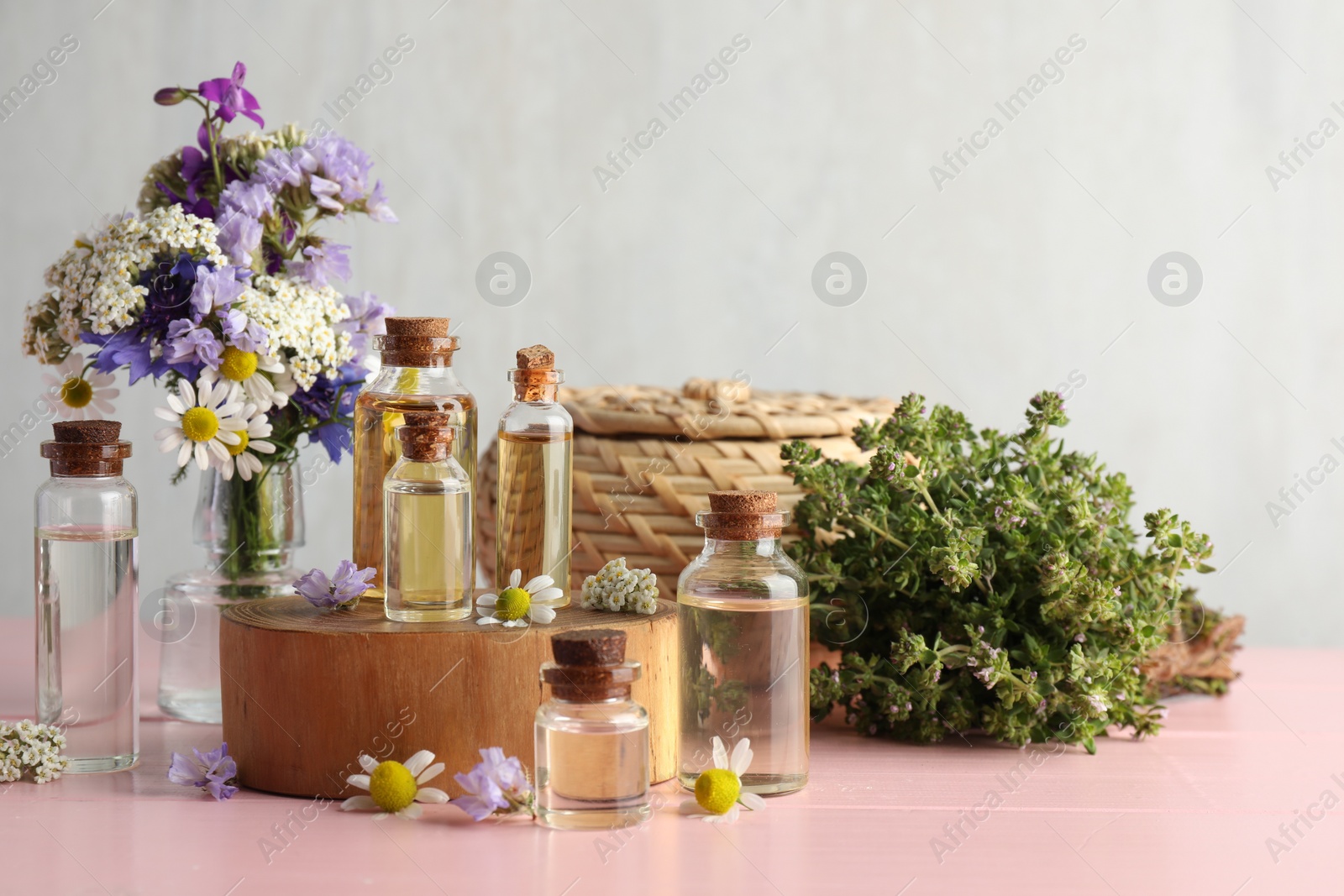 Photo of Aromatherapy. Different essential oils and flowers on pink wooden table