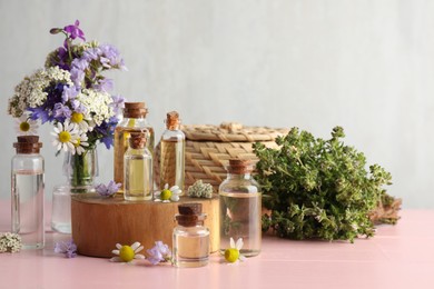 Aromatherapy. Different essential oils and flowers on pink wooden table