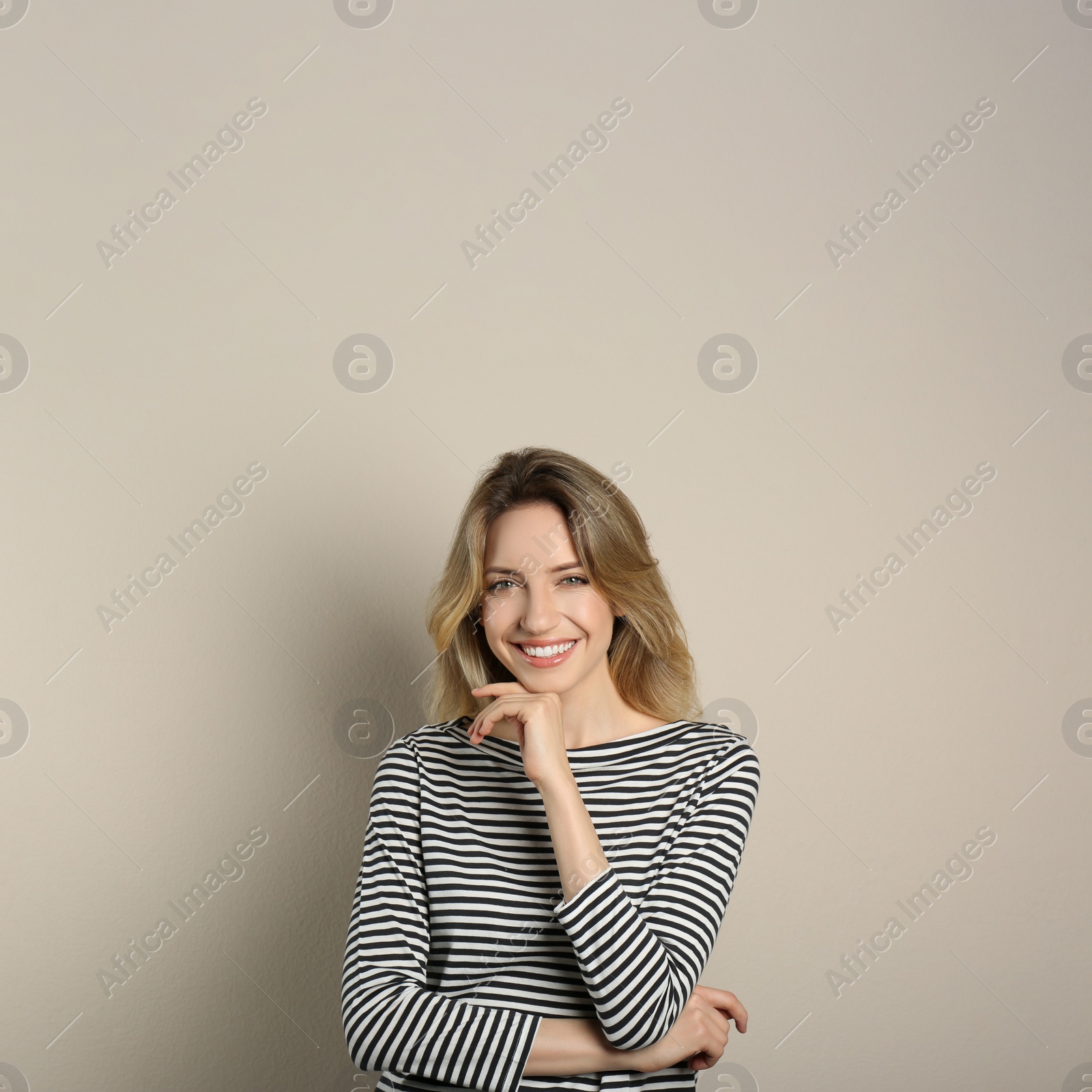 Photo of Portrait of happy young woman with beautiful blonde hair and charming smile on beige background