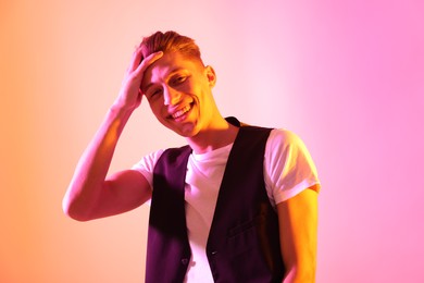 Photo of Stylish young man on pink background in neon lights