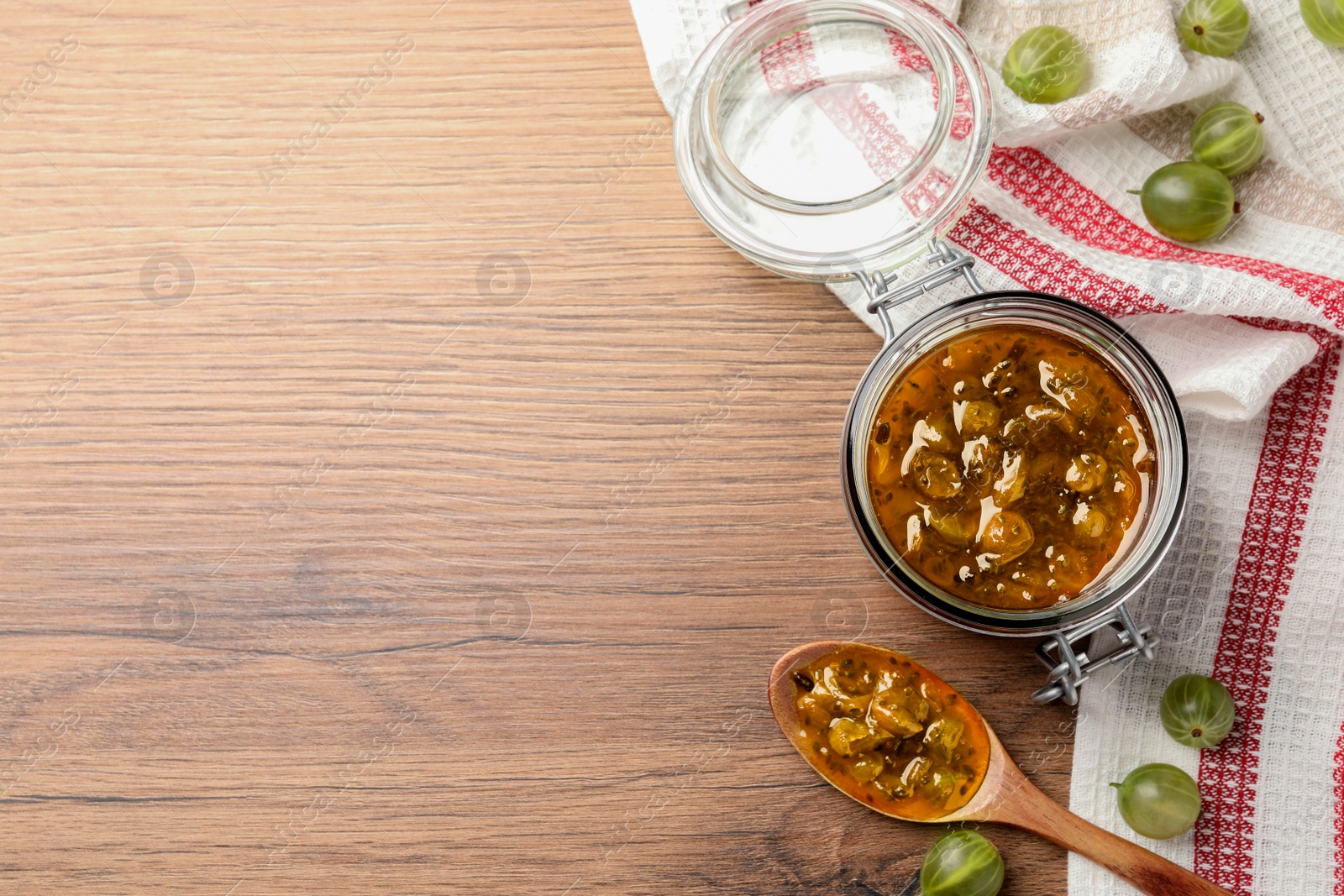 Photo of Delicious gooseberry jam and fresh berries on wooden table, flat lay. Space for text