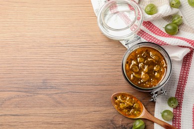 Delicious gooseberry jam and fresh berries on wooden table, flat lay. Space for text