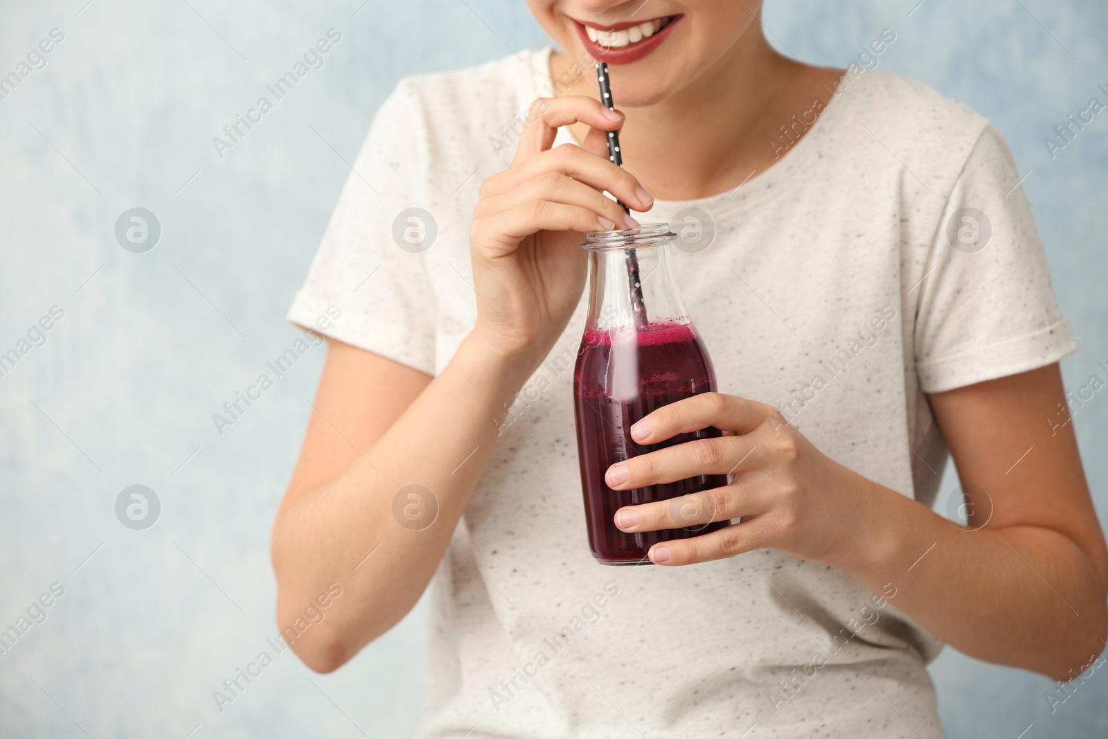 Photo of Woman with bottle of beet smoothie on light background, closeup