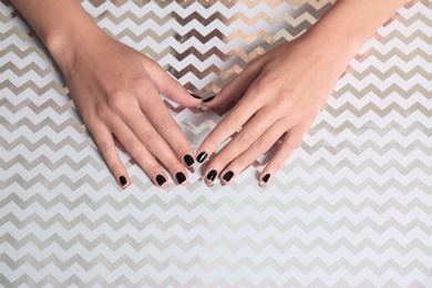 Woman with black manicure on shining background, top view. Nail polish trends