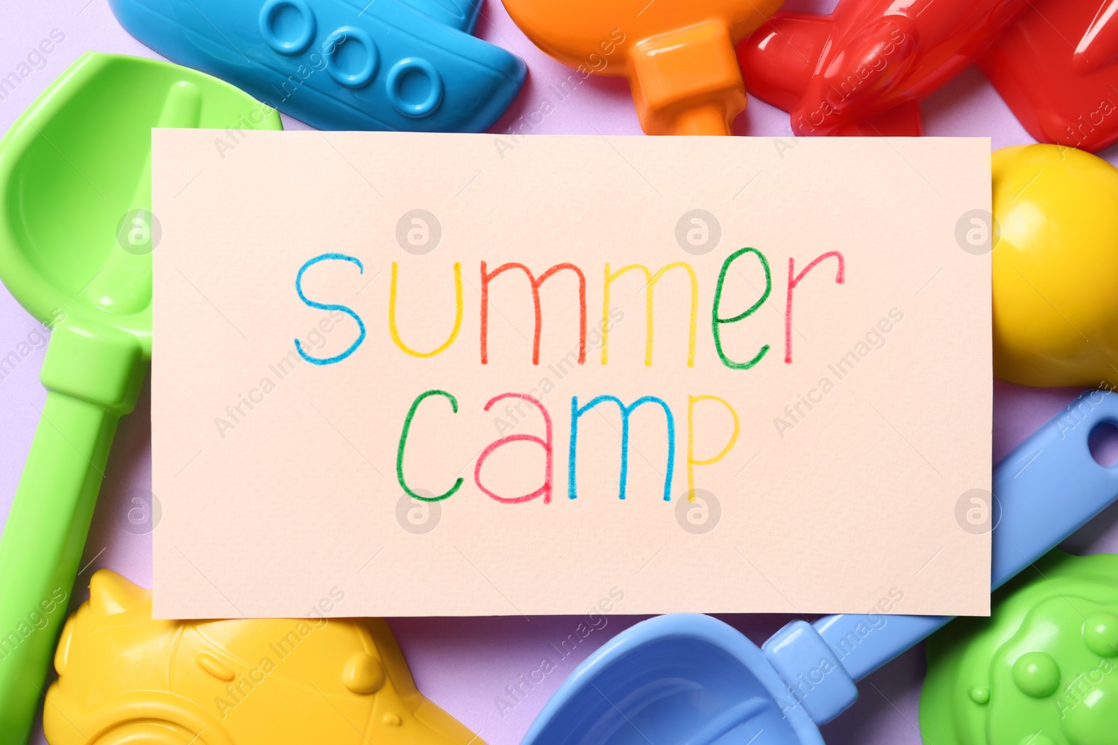 Photo of Card with text SUMMER CAMP and different sand molds on color background, flat lay