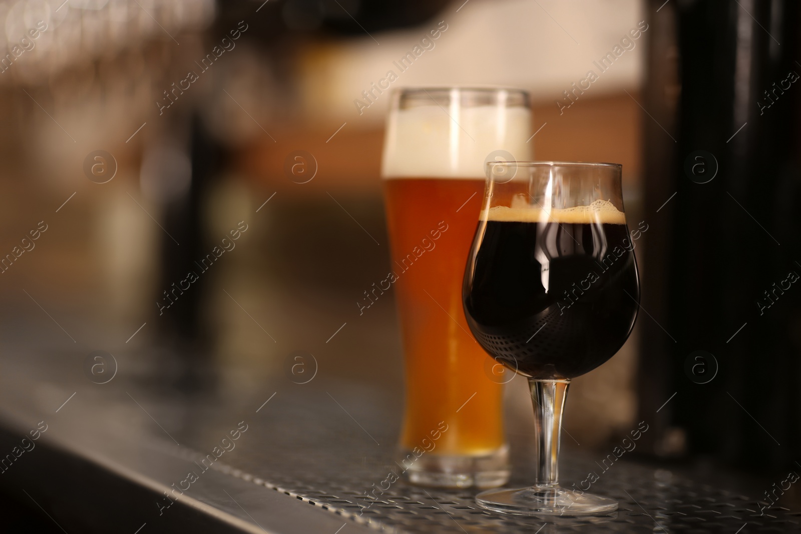 Photo of Different beers in glasses on bar counter, space for text