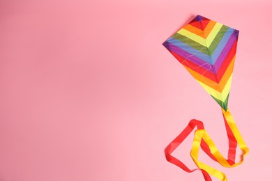 Photo of Bright rainbow kite on pink background, top view. Space for text