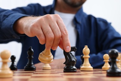 Man moving knight on chessboard indoors, closeup