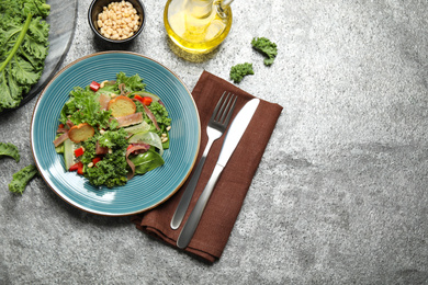 Photo of Delicious kale salad on grey table, flat lay. Space for text