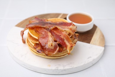 Photo of Delicious pancakes with bacon and honey on white table, closeup