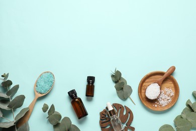 Photo of Aromatherapy products. Bottles of essential oil, sea salt and eucalyptus branches on light blue background, flat lay. Space for text