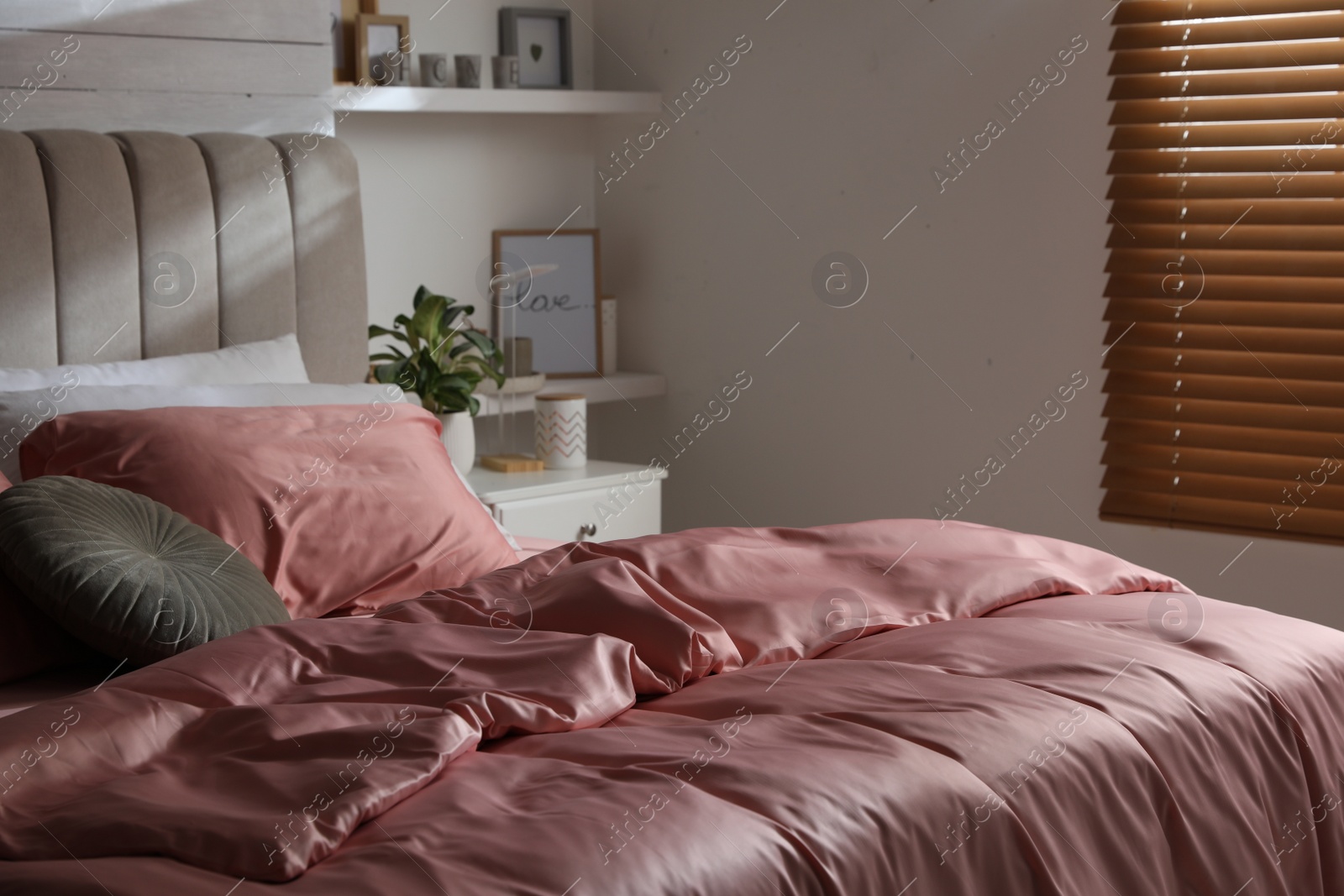 Photo of Bed with beautiful silky linens in stylish room interior