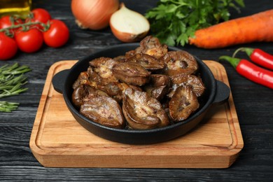 Photo of Frying pan with delicious kidneys on black wooden table, closeup