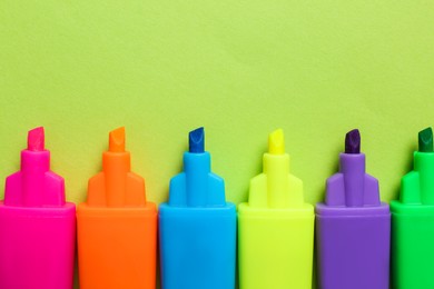 Set of highlighters on light green background, flat lay