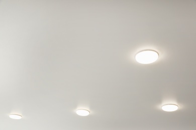 Photo of White ceiling with lamps indoors, below view