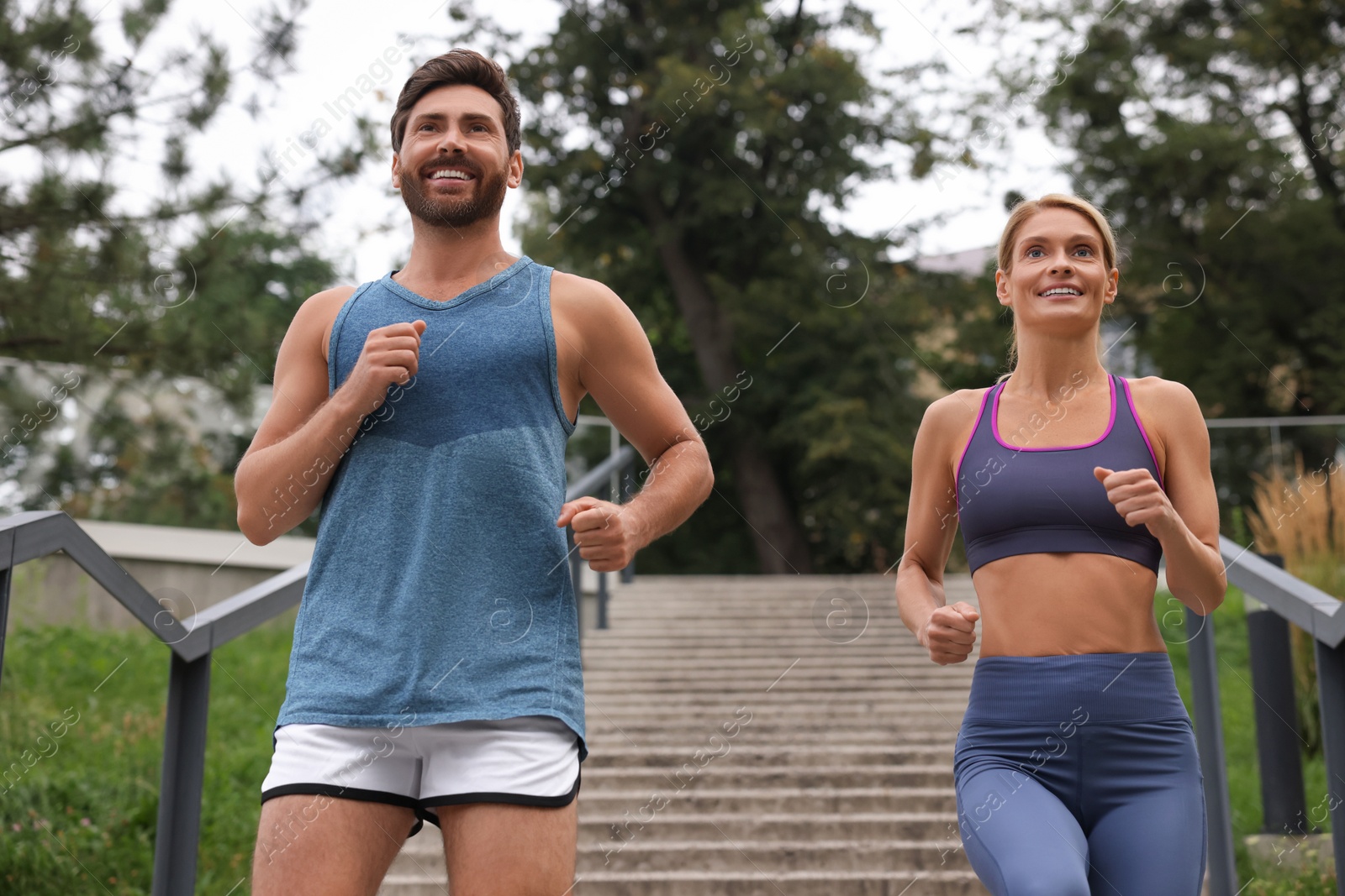 Photo of Healthy lifestyle. Happy couple running down stairs outdoors